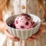 Kind hält eine Schüssel mit selbstgemachtem Kirsch-Joghurt-Eis. Das cremige Kirschen Rezept ist ein einfaches Sommerdessert und perfekt für heiße Sommertage.
